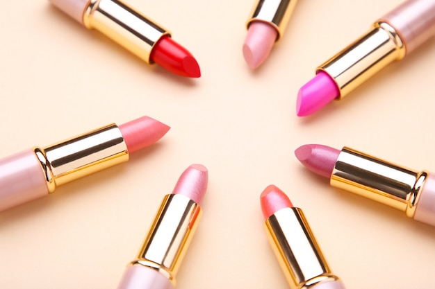 Many colorful lipstick on beige, flat lay