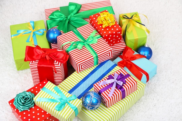 Many colorful presents with luxury ribbons on color carpet background