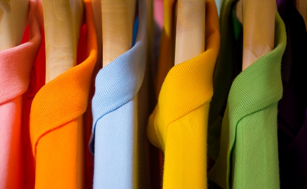 Many colorful shirts hanging on a rack