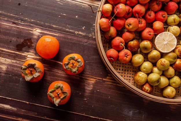 Photo many colors and varieties of fruit are either on the plate or scattered on the wooden table