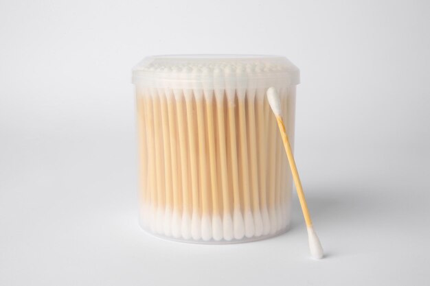 Many cotton buds in container on white background