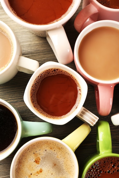 Many cups of coffee on wooden table, top view