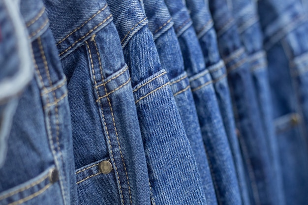 Many denim jeans hanging on a rack