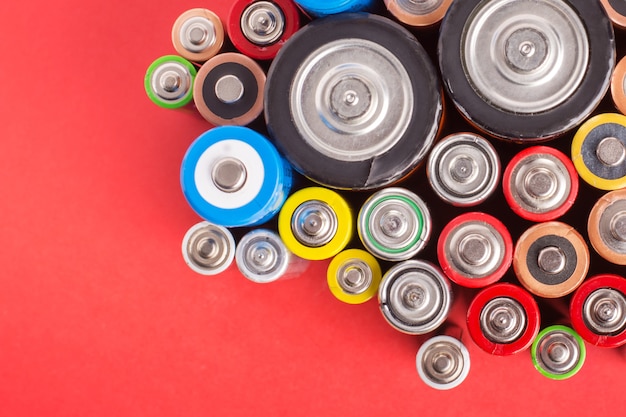 Many different alkaline batteries on a red background