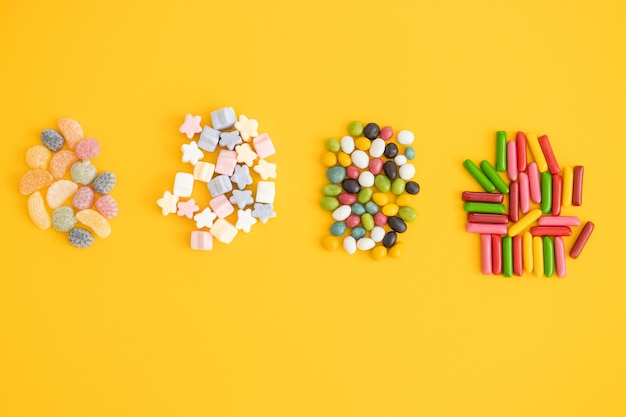 Many different candies and sweets on yellow background