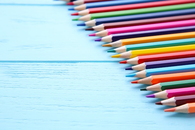 Many different colored pencils on blue wooden background