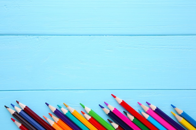 Many different colored pencils on blue wooden 