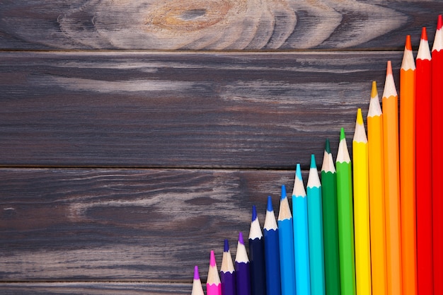 Many different colored pencils on wooden table