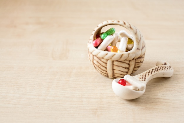 Many different colored pills, and capsules in ceramic vase