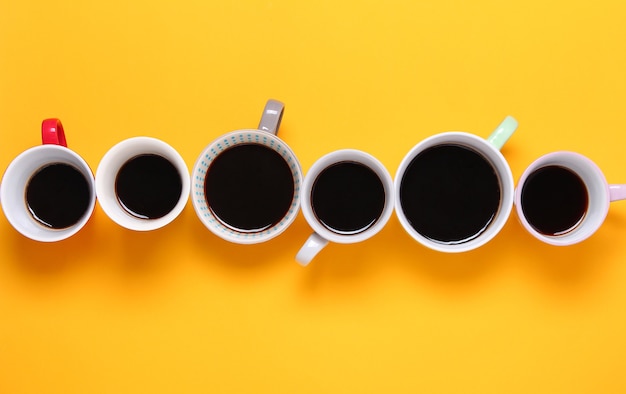 Many different cups of coffee on yellow background. Top view,flat lay,copy space.