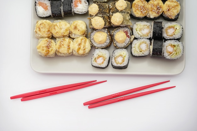 접시에 많은 다른 맛있는 일본 스시 롤과 롤에 대한 빨간 막대기