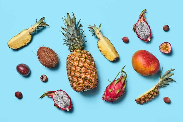 Many different exotic fruits whole and halves presented on a blue background flat lay