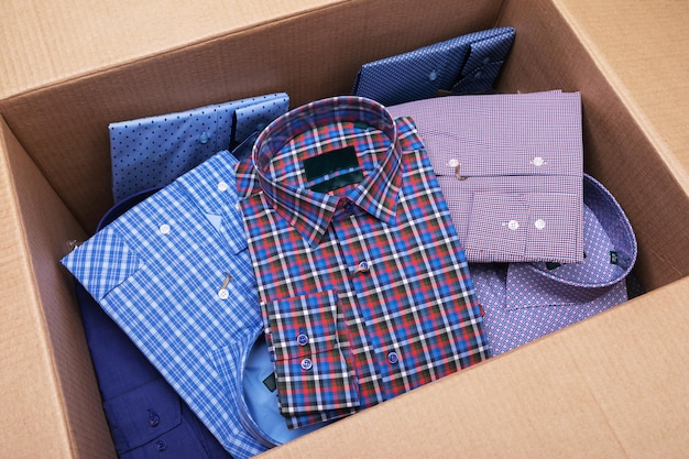 Many different folded long sleeve shirts in an open box