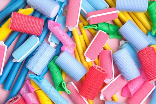 Many different hair curlers on pink background flat lay