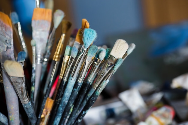 Many different painting brushes in the artist's workspace