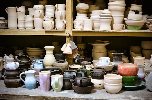 Много разных керамических изделий стоит на полках в мастерской
