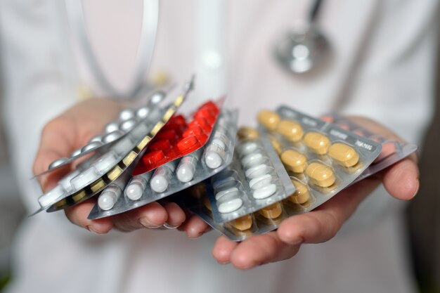 many different types of pills in the palm of female doctor