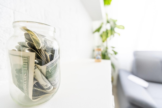 Many dollars bank notes in a glass jar isolated on white background.