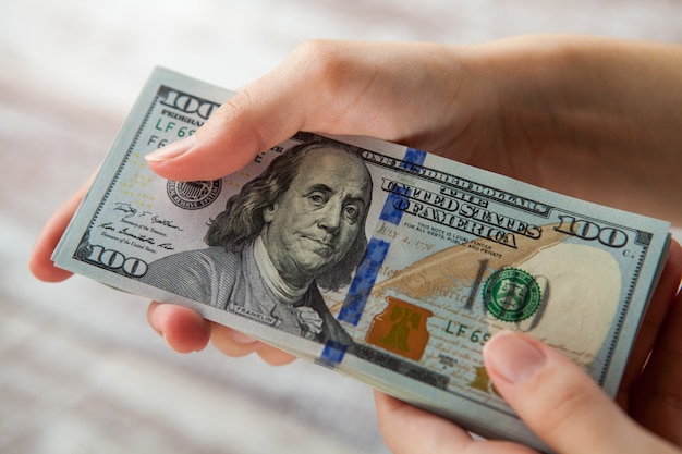 many dollars falling on woman's hand with money
