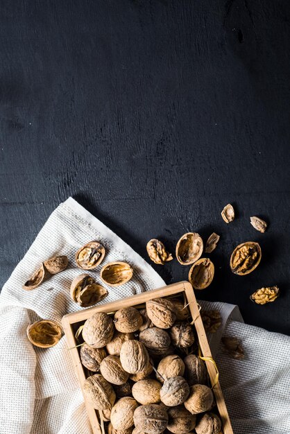 Many dry nuts in wooden box on black background. Copy space