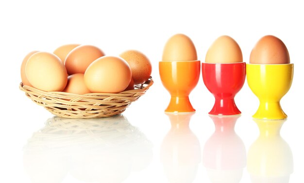 Много яиц в корзине и в чашке для яиц, изолированных на белом