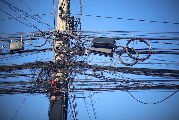 Photo many electrical and communication cables are entangled in a mess on the power poles confusing and insecure concept to operate and manage the system