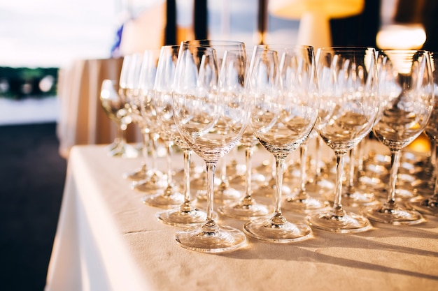 Many empty champagne glasses close up. glass goblets on the white table. Empty crystal wine glass. glass goblet on a high leg.