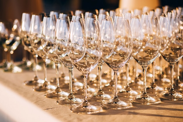 多くの空のシャンパングラスをクローズアップ。白いテーブルの上のガラスのゴブレット。空のクリスタルワイングラス。高い脚にガラスの杯。