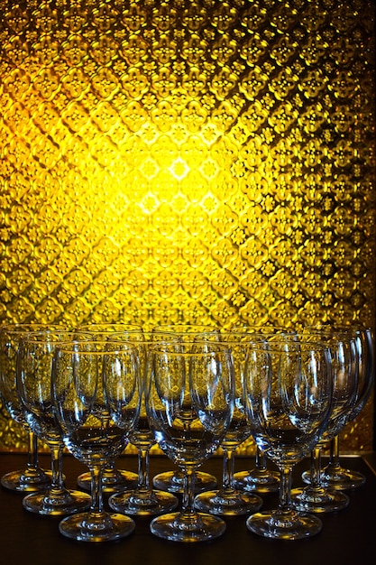 Many Empty Wine Glass in order on table and yellow back light as glass facet background