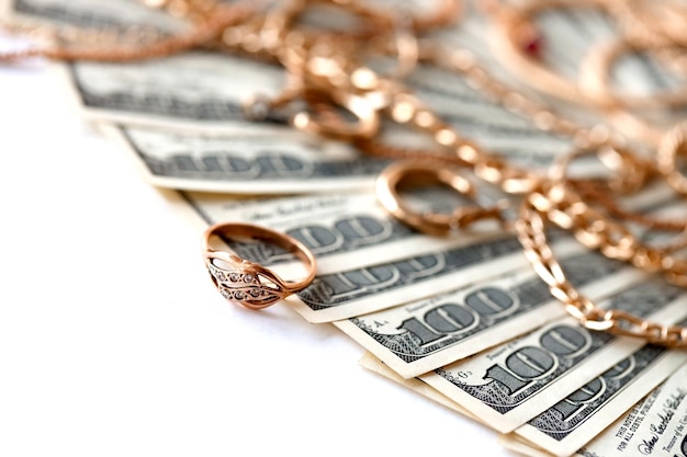 Photo many expensive golden jewerly rings earrings and necklaces with big amount of us dollar bills on white background pawnshop or jewerly shop