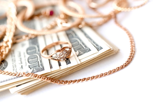 多くの高価な金色の宝石の指輪イヤリングとネックレス、白い背景に大量の米ドル札が付いている質屋または宝石店
