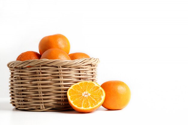 Many fresh oranges in a wooden basket placed on the floor.