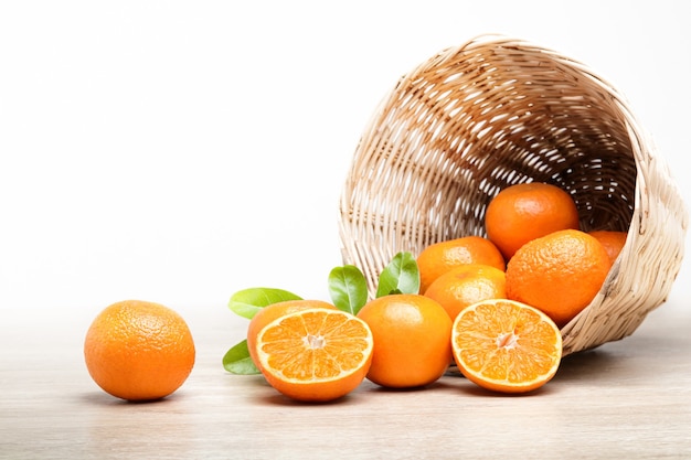 Many fresh oranges in a wooden basket placed on the floor.