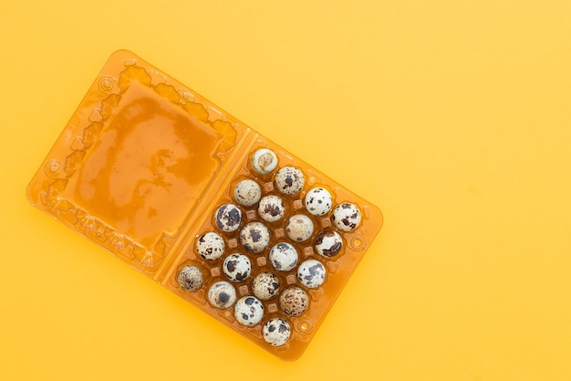 Many fresh quail eggs on yellow background closeup