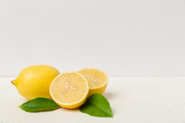 Many fresh ripe lemons with green leaves on colored background top view space for text