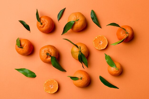 Many fresh ripe mandarin as colored background top view Elegant background of clementines and mandarin slices Top view flat lay