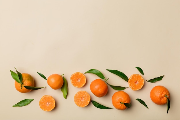 Many fresh ripe mandarin with green leaves on colored background top view space for text