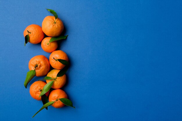 Photo many fresh ripe mandarin with green leaves on colored background top view space for text