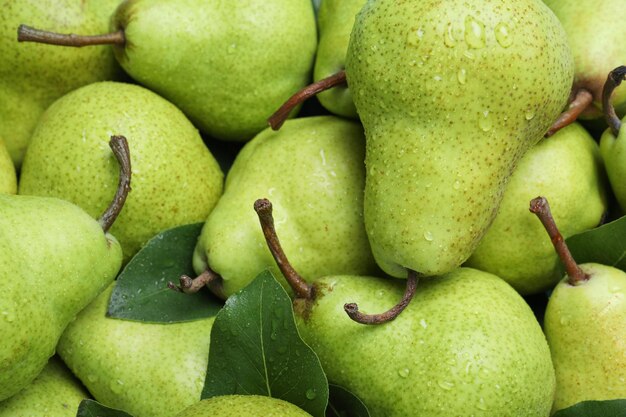 Many fresh ripe pears with water drops as background closeup