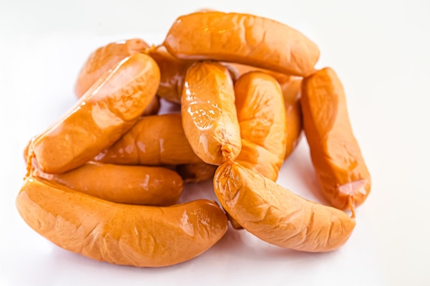 many fresh whole sausages lie on a white background isolated