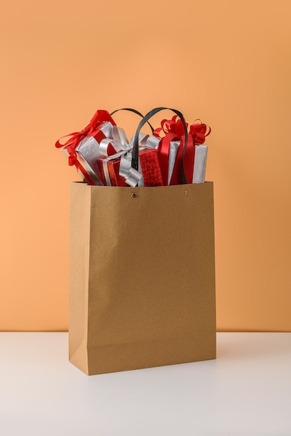 Many Gift Box with Red ribbon bow in Brown paper shopping bag. concepts New Year's gift or Christmas