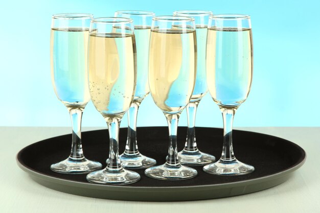 Many glasses of champagne on the tray on table on blue background