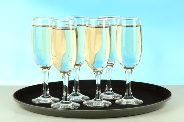 Many glasses of champagne on the tray on table on blue background