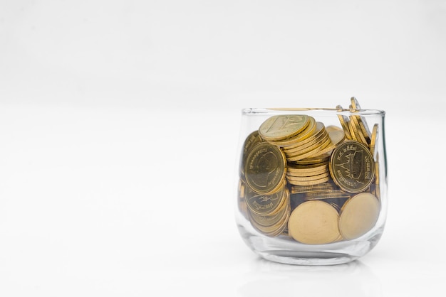 Photo many gold coins in glass on white background