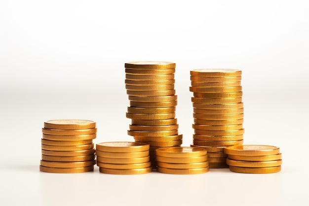 Many golden coins stacked on wooden table against white background