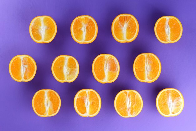 Many halves of sweet juicy oranges on a purple background closeup of tropical fruits background