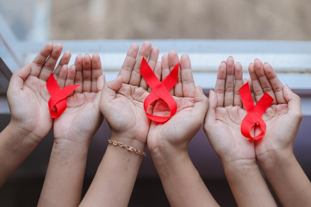 Photo many hands holding red ribbons for aids or cancer campaign background