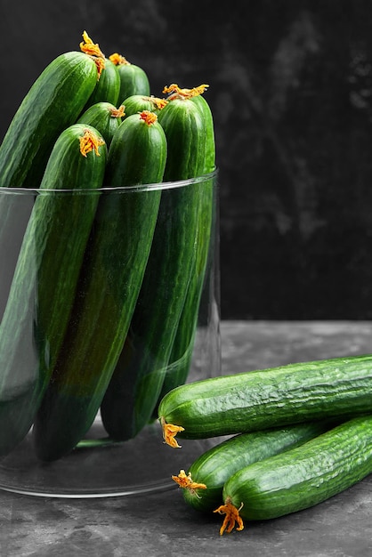 Many harvest cucumbers in vase on the grey concrete background. Top view,