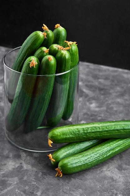 Many harvest cucumbers in vase on the grey concrete background. top view,