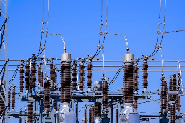 Many high voltage electrical insulators in power substation against blue sky background